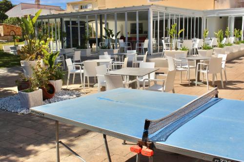a ping pong table on a patio with tables and chairs at Bluewater Hotel in Colonia Sant Jordi