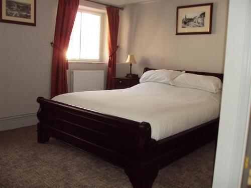 a bedroom with a large bed with white sheets and a window at The George Inn in Mere