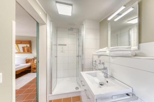 a white bathroom with a shower and a sink at Natur pur! Exklusive Ferienwohnungen in historischer Poststation Bornkrug in Linstow