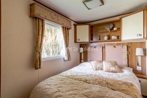 a bedroom with a bed and a window at Lovely Caravan For Hire With Decking At Skipsea Sands In Yorkshire Ref 41015wf in Barmston