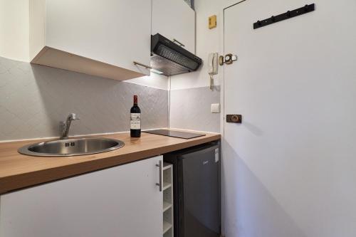 - une cuisine avec un évier et une bouteille de vin dans l'établissement Le Marquis - T1 - 5 mins de la Cathédrale, à Reims