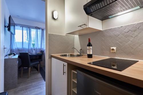 une cuisine avec un évier et une bouteille de vin sur un comptoir dans l'établissement Le Marquis - T1 - 5 mins de la Cathédrale, à Reims