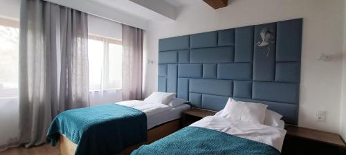 a bedroom with two beds and a blue headboard at Podzamcze in Rożnów