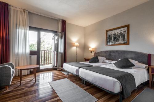 um quarto de hotel com duas camas e uma varanda em Snö Hotel Formigal em Formigal