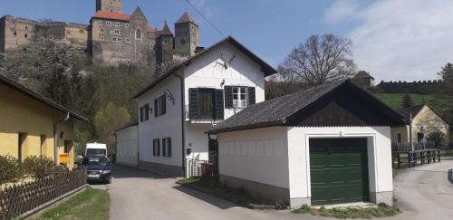 a white house with a green garage in front of a castle at Burgblick-Hardegg in Hardegg