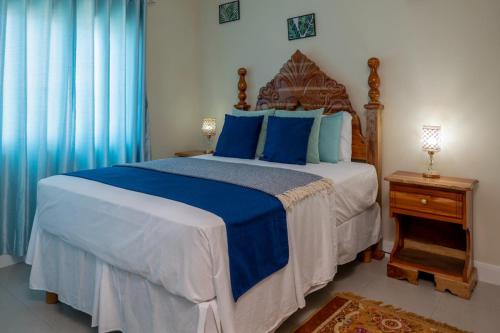 a bedroom with a large bed with blue pillows at Hamilton @ Oceanpointe a serene 2bed 2 bath Villa in Lucea
