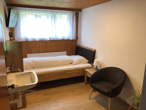 a bedroom with a bed and a sink and a chair at Hotel Sonne in Wildhaus