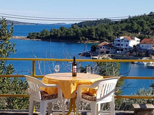 a table with a bottle of wine and two chairs at ISLAND OASIS - apartment with large bedroom & terrace with amazing sea view in Zaglav