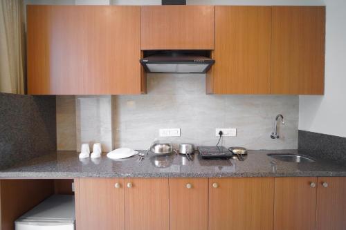 a kitchen with wooden cabinets and a counter top at Saltstayz Executive Studio Apartment in Gurgaon