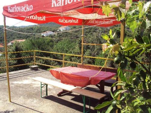 einen Picknicktisch mit einem roten Regenschirm und einer Bank in der Unterkunft ISLAND OASIS - apartment with large bedroom & terrace with amazing sea view in Zaglav