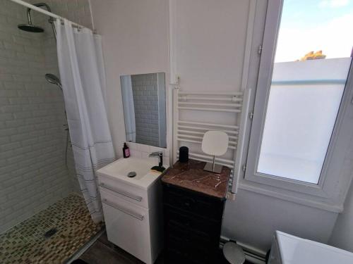 une salle de bain blanche avec un lavabo et un miroir dans l'établissement Le Carillon Dieppois, à Dieppe