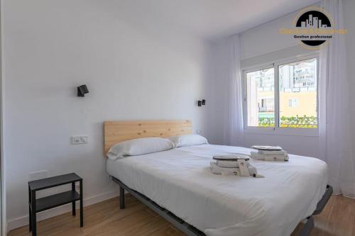 a white bedroom with a large bed and a window at Apartamento El SolAire centro Torremolinos in Torremolinos