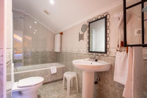 a bathroom with a sink and a toilet and a tub at Posada El Trasmerano in Argoños