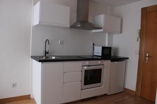 a white kitchen with a sink and a microwave at Adosinda Suite in Gijón