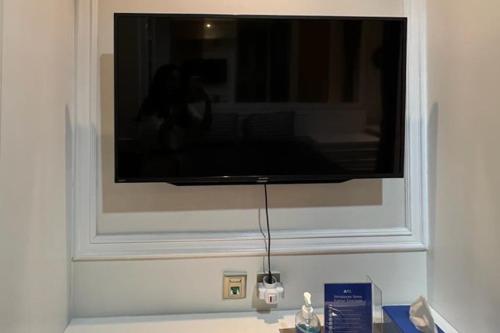 einen Flachbild-TV, der an einer Wand hängt in der Unterkunft RedLiving Apartemen Transpark Cibubur - Ens Room in Depok