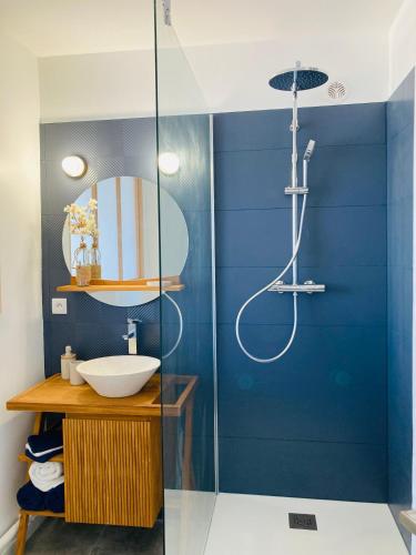 La salle de bains bleue est pourvue d'un lavabo et d'une douche. dans l'établissement Rêve Salé Appartement Vue Mer 2 à 4 pers, à Dieppe