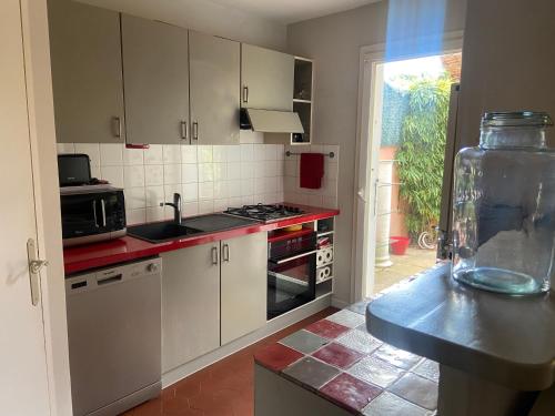 une cuisine avec des placards blancs et un comptoir rouge dans l'établissement Maison 6 pers. A 5 mn du lac, à Montauroux