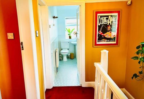 a bathroom with a toilet and a poster on the wall at Liverpool - Cosy Jazzy Beach Home! in Waterloo