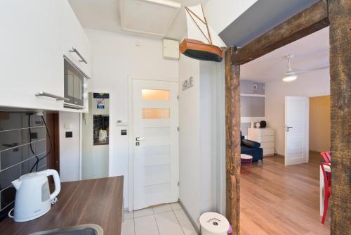 a kitchen and living room with white walls and wood floors at Kawalerka Studio Stare Domki krr in Gdańsk