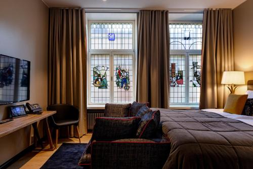 a bedroom with a bed and a desk and windows at Hotel F6 in Helsinki