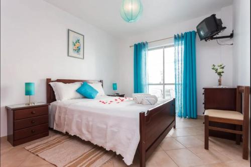 a bedroom with a large bed with blue curtains at Apartamento Férias Lagos in Lagos