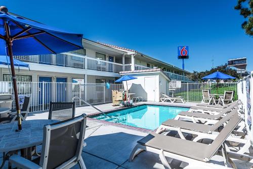 a swimming pool with chairs and a table with an umbrella at Motel 6-Sparks, NV - Airport - Sparks in Reno