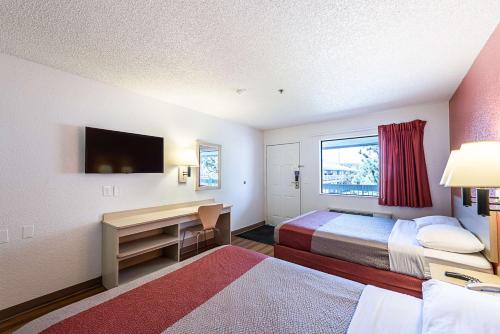 a hotel room with two beds and a desk and a television at Motel 6-Sparks, NV - Airport - Sparks in Reno