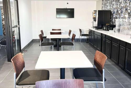 a dining room with tables and chairs and a kitchen at Super 8 by Wyndham Peoria in Peoria