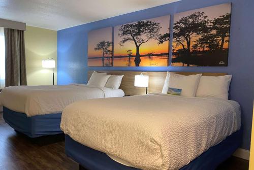 2 camas en una habitación de hotel con pinturas en la pared en Days Inn by Wyndham Fordyce, en Fordyce