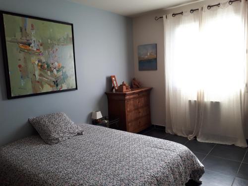 um quarto com uma cama e um quadro na parede em Villa climatisée avec piscine proche de la mer em Torreilles