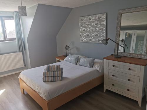a bedroom with a bed with a mirror and a dresser at Spacious Family Friendly Apartment- 100m from beach with Seaviews! in Hunstanton