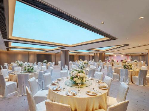 um salão de banquetes com mesas brancas e cadeiras brancas em Novotel Century Hong Kong em Hong Kong