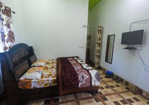 1 dormitorio con 1 cama y TV. en Gaharwar Home Stay, en Dehradun