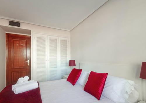 a white bed with red pillows in a bedroom at Cituspace Cuzco in Madrid