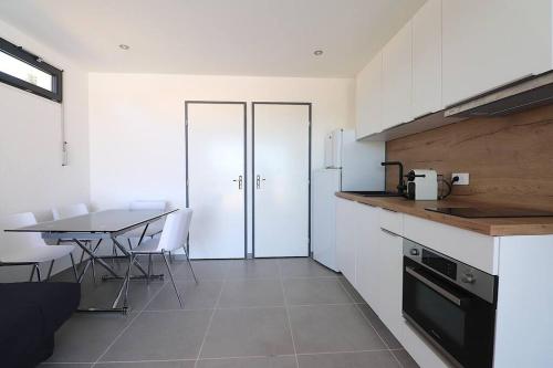AlbitrecciaT2 VILLAS ACUM 4 pers-Agosta PLAGE- parking的厨房配有白色橱柜和桌子及椅子