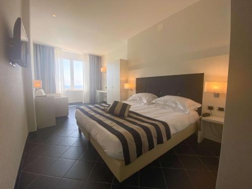 a bedroom with a large bed with a striped blanket at Best Western Hotel Acqua Novella in Spotorno