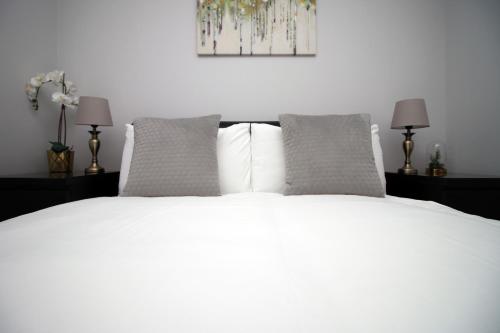 1 dormitorio con 1 cama blanca y 2 almohadas en Violet's Corner Luxury Apartment by StayStaycations en Swindon