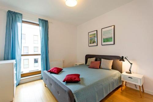 Un dormitorio con una cama con almohadas rojas. en Nadmorski Dwór by Grand Apartments en Gdansk