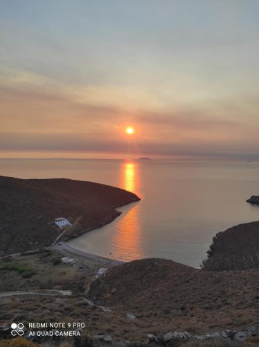 a sunset over a beach with the sun setting over the water at Villa Mavrianos in Kithnos