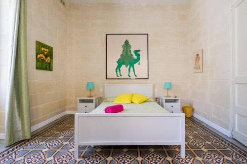 Un dormitorio con una cama blanca con dos mesas y un caballo en la pared. en Enjoy and Relax at the Blu House, en Sliema