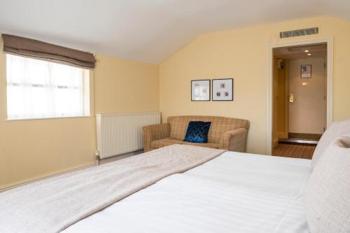 a bedroom with a bed and a couch and a window at St George's Hotel - Llandudno in Llandudno