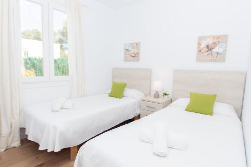 2 Betten in einem weißen Zimmer mit Fenstern in der Unterkunft Villa Ohana by Sonne Villas in Cala Galdana