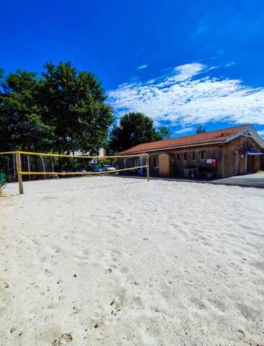 un filet de volley-ball dans le sable devant un bâtiment dans l'établissement Village Drôles d'Oiseaux, au Teich