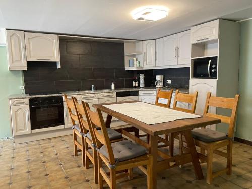 una cocina con armarios blancos y una mesa y sillas de madera. en La bergerie, en La Bruyère