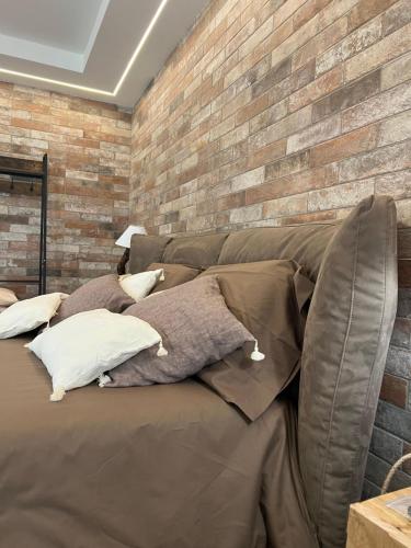 a bed with pillows and a brick wall at Le Dimore Del Gufo - Royal Suite in Venosa