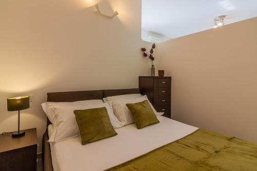1 dormitorio con 1 cama con sábanas blancas y almohadas verdes en Anzani Modern Studio by Wonderful Italy en Como