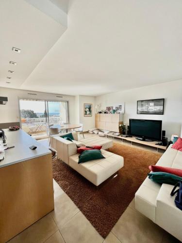 un salon avec des canapés, une table et une télévision dans l'établissement Antibes Maeva sea view swimming pool air conditioning and parking, à Antibes