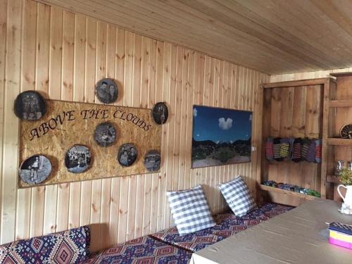 een kamer met een houten muur met een tafel en kussens bij Above the Clouds in Tusheti