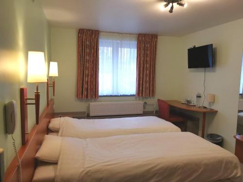 ein Hotelzimmer mit 2 Betten und einem TV in der Unterkunft Hotel Aux Beaux Rivages En Gaume in Lacuisine