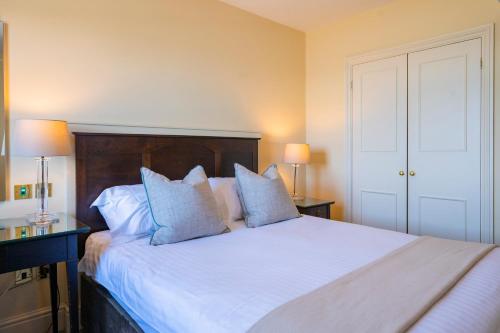 a bedroom with a large white bed with blue pillows at St George's Hotel - Llandudno in Llandudno